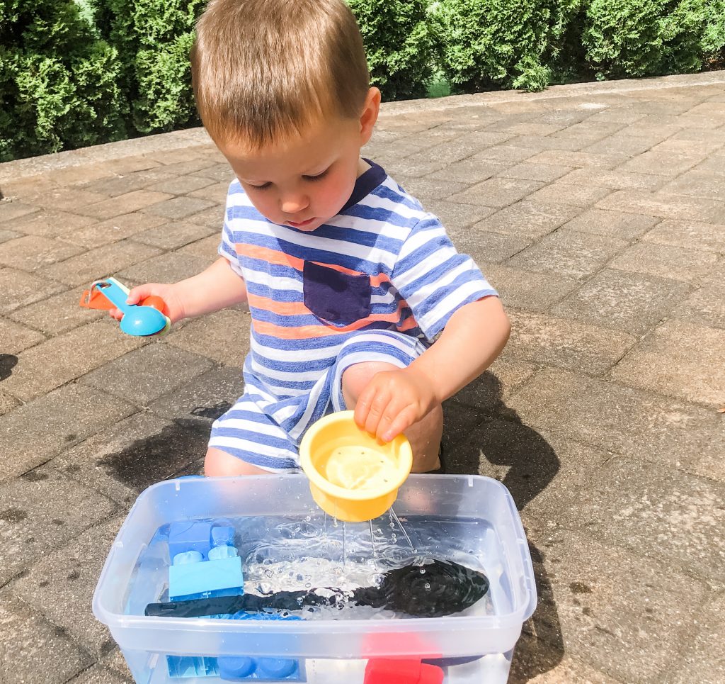 A simple sensory outdoor activity for your toddlers or babies. Use a spoon to scoop small toys out of a container of water for fun outside play.