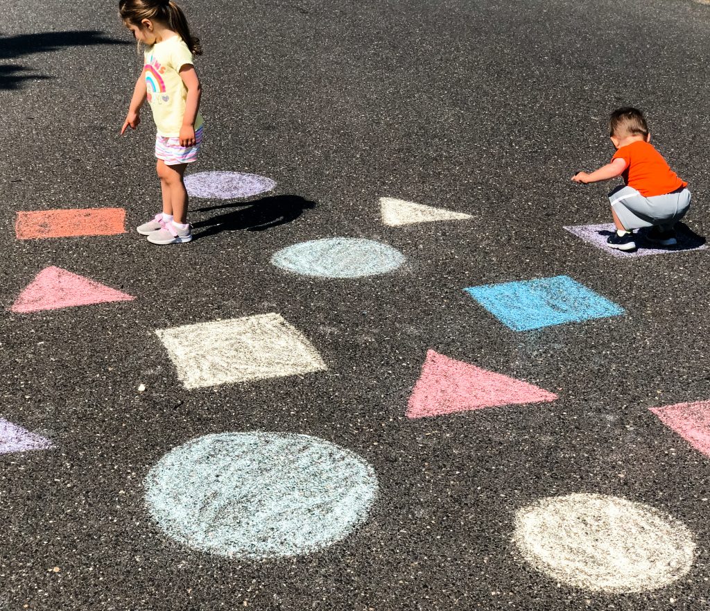 This sidewalk chalk shape & color learning game & activity incorporates gross motor & cognitive skills while your toddler or preschooler is outside playing