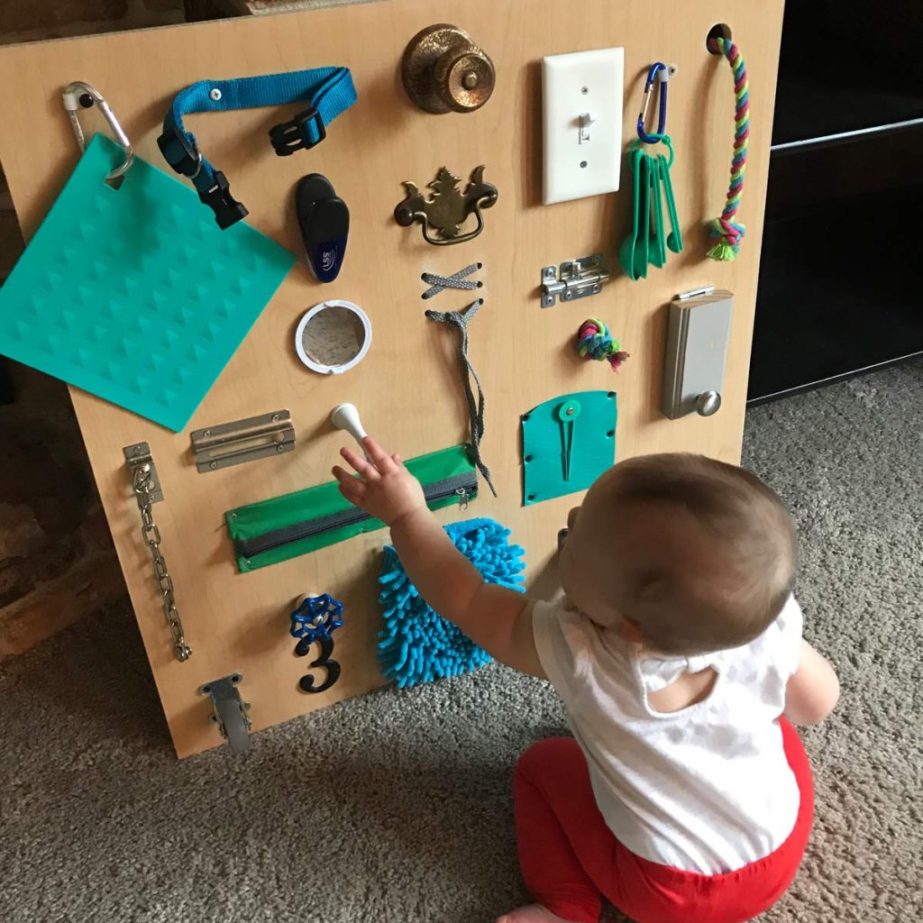 Get creative by making your own toddler busy board for your child so they can learn & explore sensory objects & toys in one place.